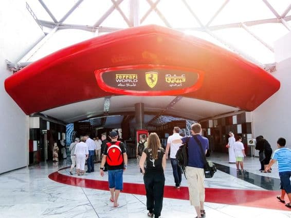 Entrada da Ferrari World Esports Arena em Abu Dhabi, pessoas entrando pela porta.