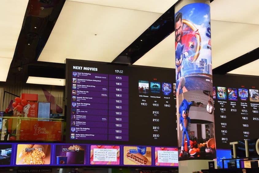 Horários de cinema exibidos no Dubai Mall mostrando os horários e locais dos filmes.
