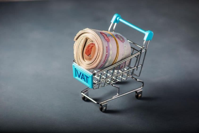 Carrinho de compras pequeno com um maço de dirham e a palavra 'imposto' na frente.