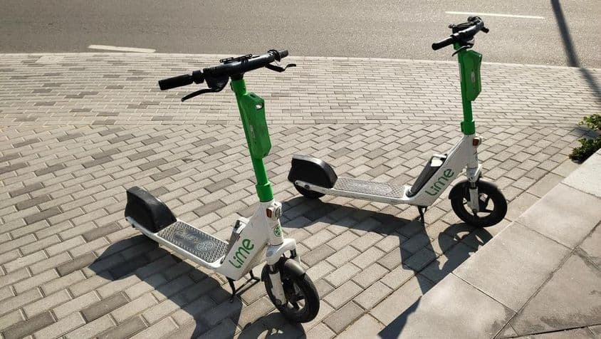 Scooters Lime estacionadas em uma rua de Dubai.