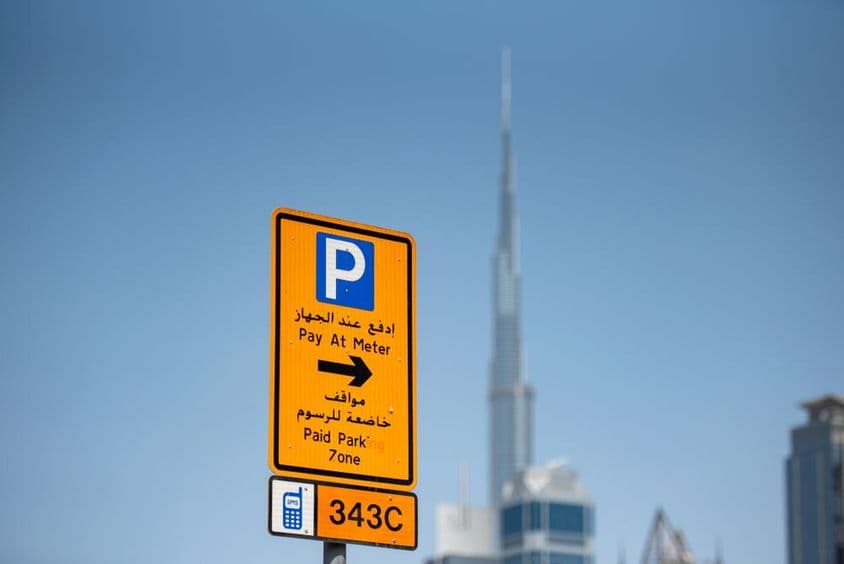 Placa de estacionamento com código de zona, Burj Khalifa ao fundo.