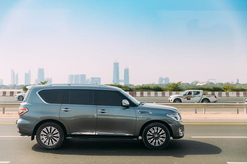 Nissan Patrol em primeiro plano com arranha-céus de Dubai ao fundo.