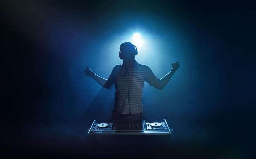 Uma pessoa está atrás da cabine do DJ.