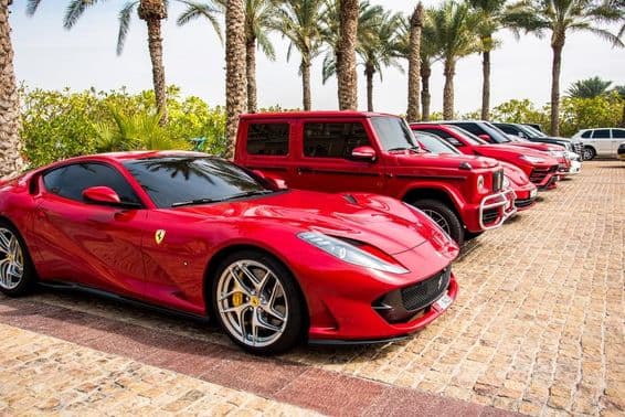 Carros de luxo vermelhos alinhados em Dubai, destacando Ferrari, Porsche, Mercedes.