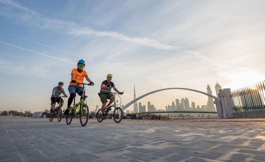 Ciclistas com capacetes em frente ao Burj Khalifa.