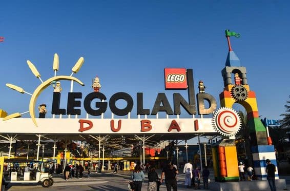Entrada do LEGOLAND Dubai com pessoas e um carrinho de golfe na frente.