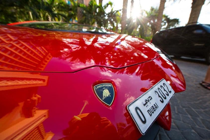 Frente de uma Lamborghini vermelha, mostrando uma placa de Dubai de quatro dígitos.