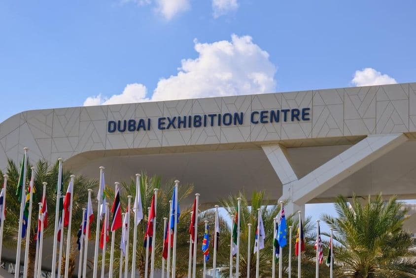 Dubai Exhibition Centre com bandeiras ao fundo.
