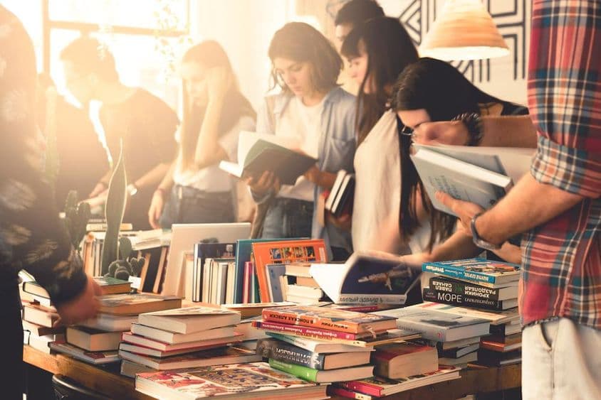 Estudantes explorando livros em uma grande feira.