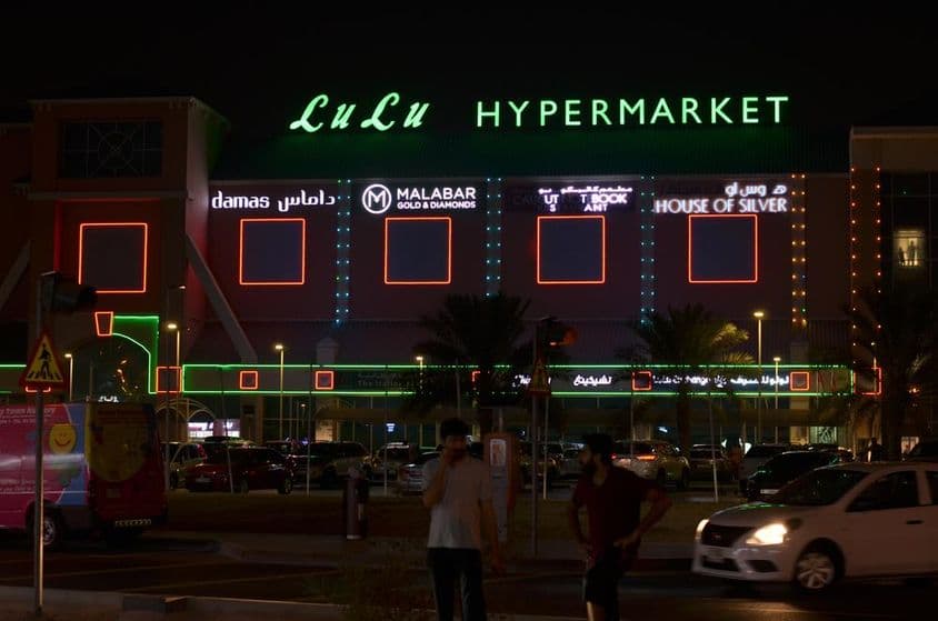 Entrada do hipermercado Lulu com letreiro de néon visível acima.