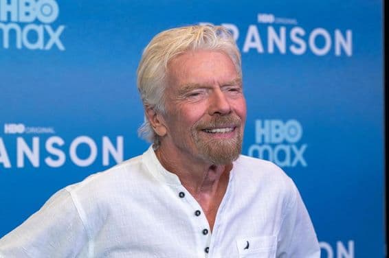 Richard Branson em frente a um fundo azul.