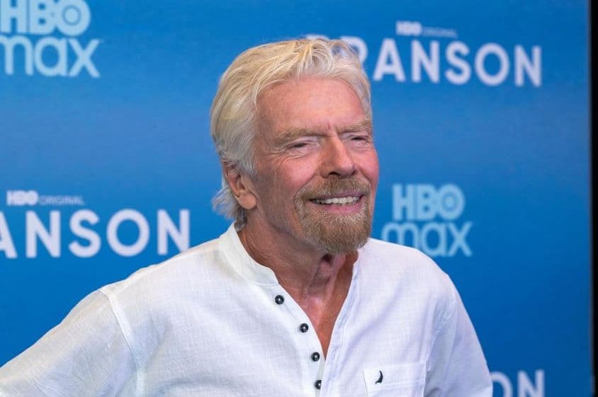 Richard Branson em frente a um fundo azul.