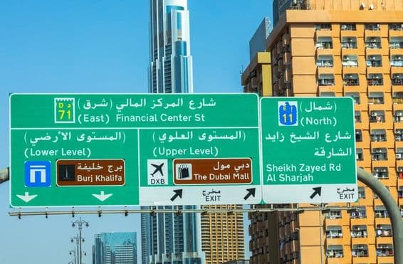 Arranha-céus de Dubai ao fundo, placa de estrada em primeiro plano.