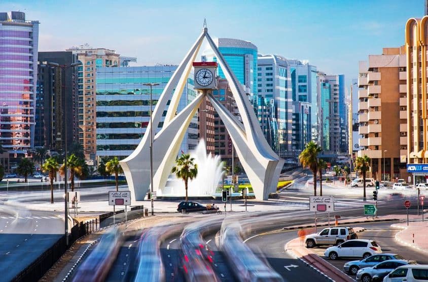 Incrível Torre do Relógio em Dubai com casas ao fundo.