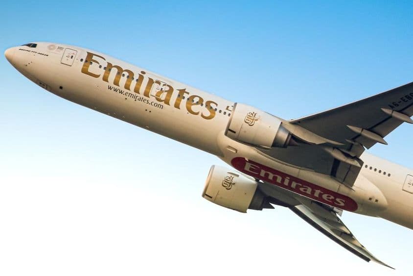 Avião da Emirates no céu, visto de baixo.