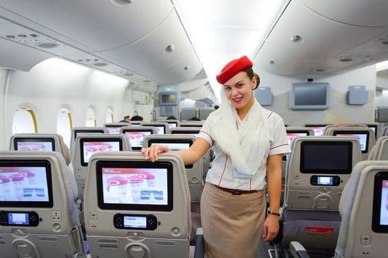 Interior de um avião Emirates com um comissário de bordo em destaque.