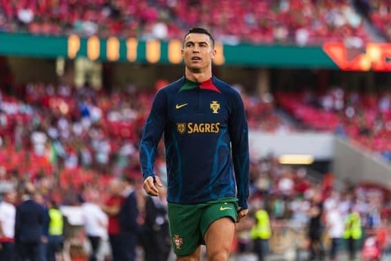 Cristiano Ronaldo em campo com um uniforme azul e shorts verdes.