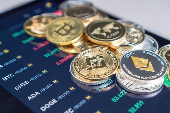 Moedas de Ethereum e bitcoin colocadas em uma tela de celular exibindo taxas de câmbio de criptomoedas.