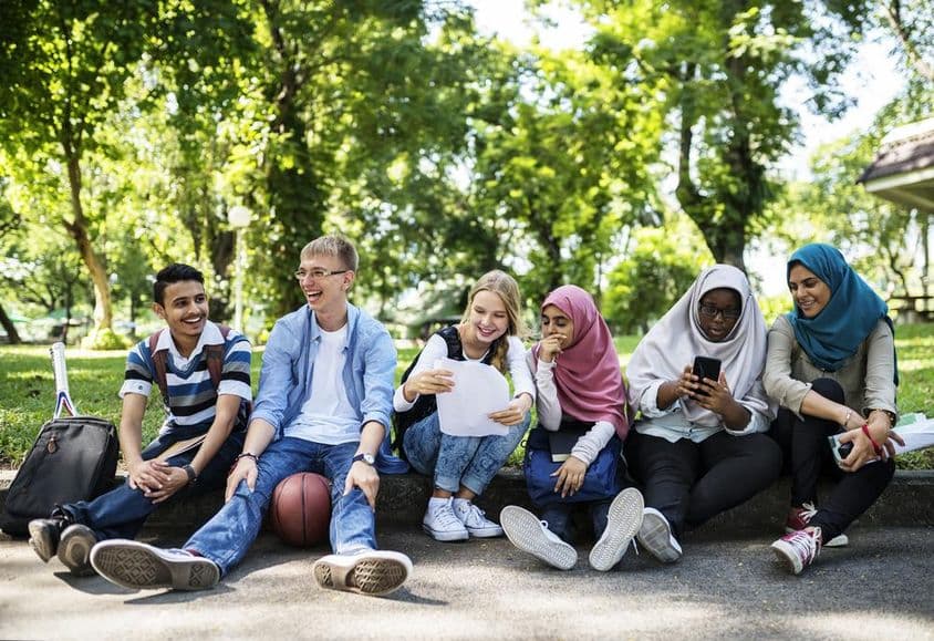 Estudantes de Dubai sentados à beira da estrada.