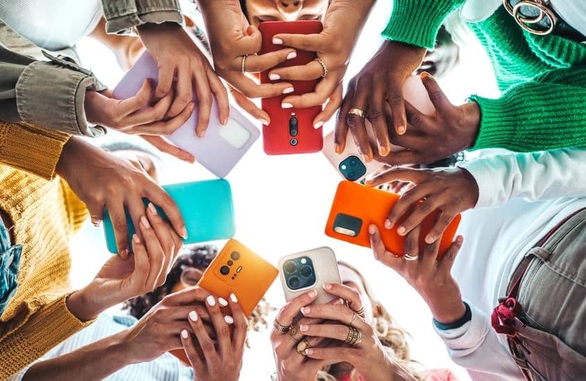 Pessoas segurando celulares em um círculo, mãos vistas de baixo.