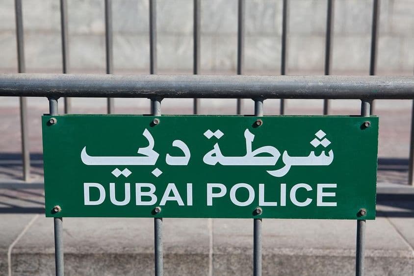 Placa da Polícia de Dubai visível em uma cerca.