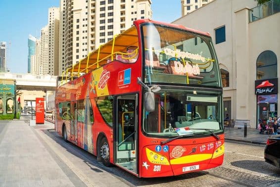 Ônibus On & Off de Dubai com arranha-céus ao fundo.