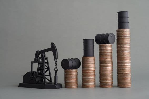 Mini plataforma de petróleo e moedas empilhadas com um barril de petróleo no topo.