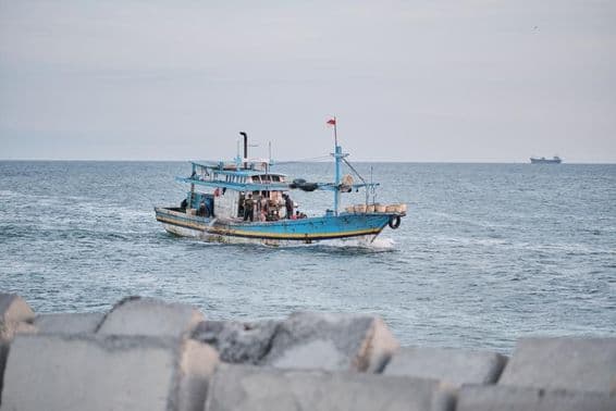 Um barco de pesca envelhecido no mar com pessoas a bordo.