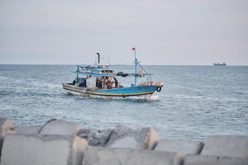 Um barco de pesca envelhecido no mar com pessoas a bordo.