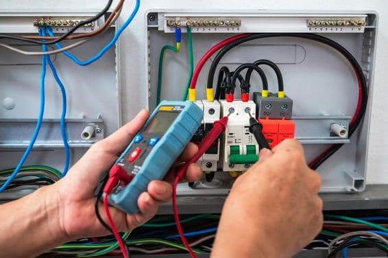 Eletricista verificando uma fonte de energia com um medidor.