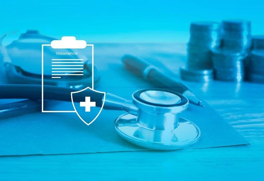 Seguro de saúde em primeiro plano, fundo com estetoscópio e moedas pequenas.