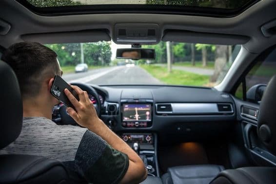 Jovem usando o celular enquanto dirige um carro.