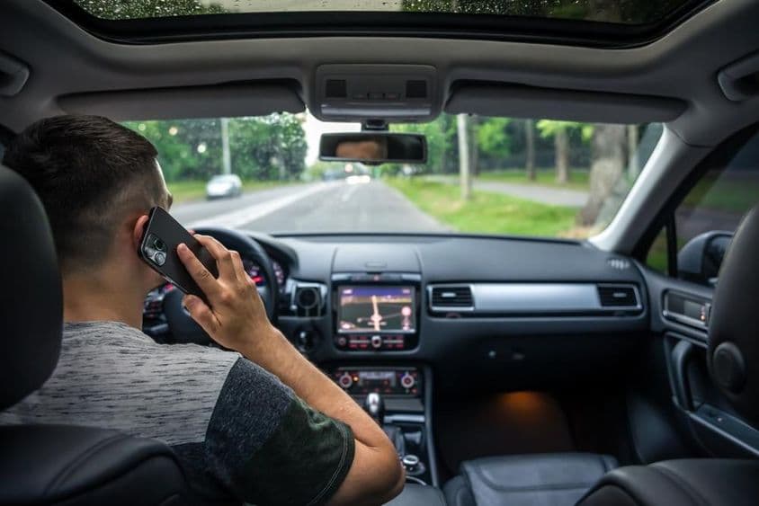Jovem usando o celular enquanto dirige um carro.