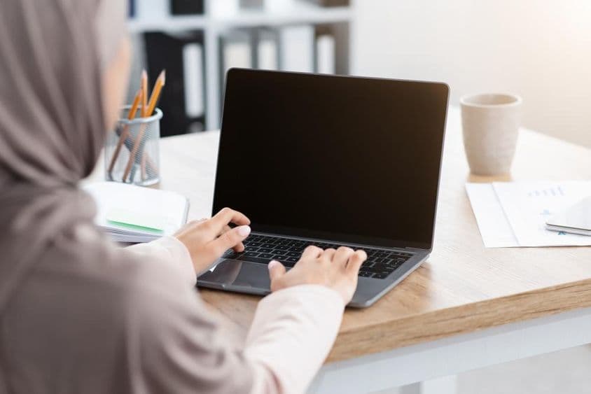Mulher muçulmana trabalhando em um laptop.