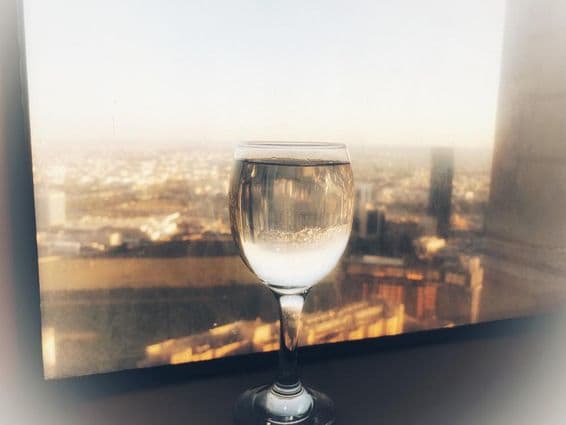 Um copo de vinho na janela com vista para a cidade.