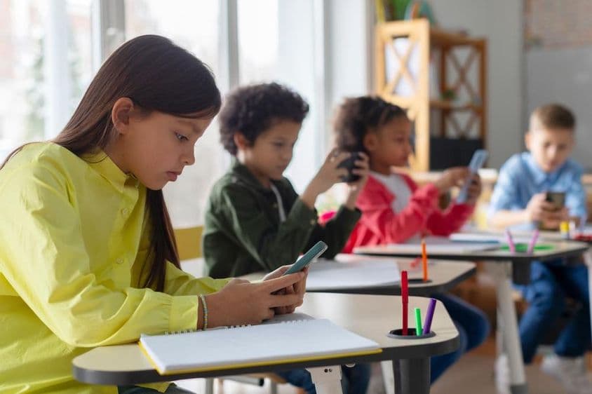 Crianças usando telefones em uma sala de aula.