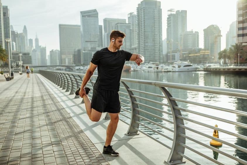 Jovem se alongando após uma corrida pelo canal de Dubai.