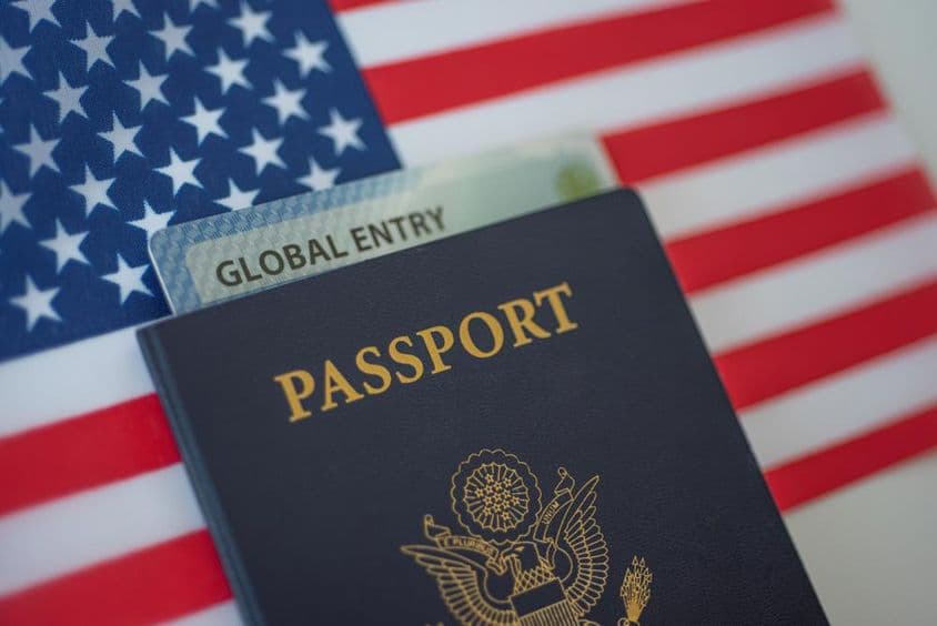 Passaporte americano com uma bandeira americana ao fundo.