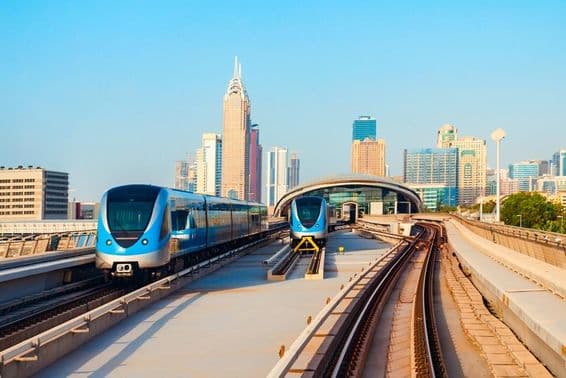 Carros do metrô de Dubai com arranha-céus ao fundo.
