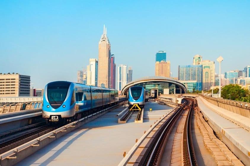 Carros do metrô de Dubai com arranha-céus ao fundo.