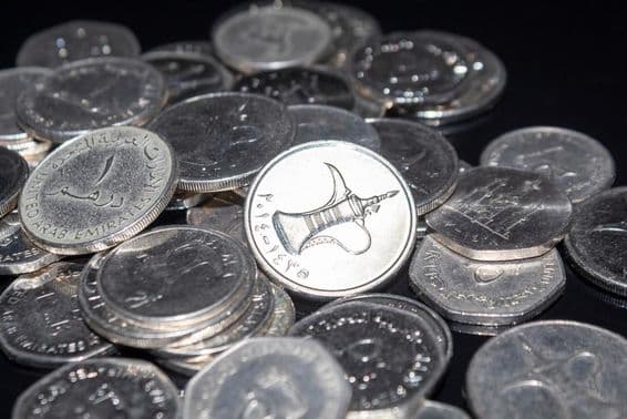 Um punhado de moedas de 1 dirham espalhadas.