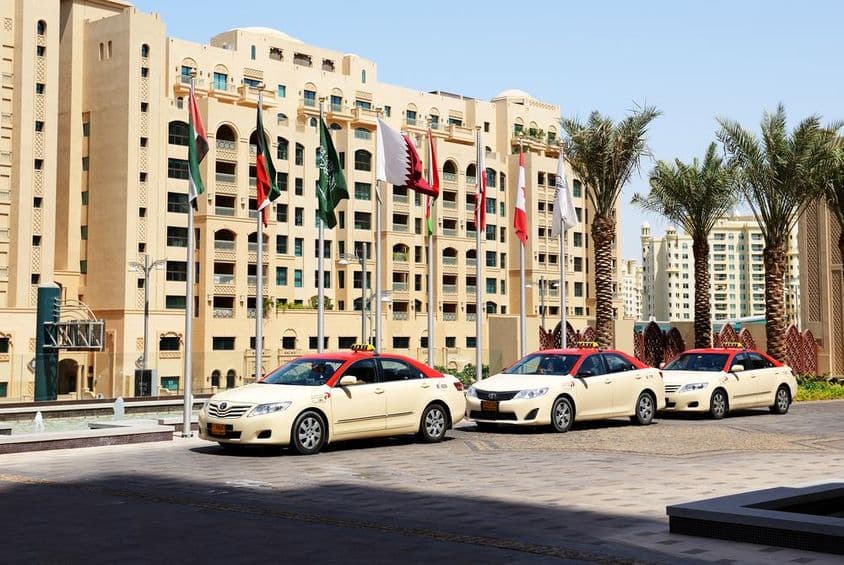 Táxis de Dubai em frente a um edifício residencial de 10 andares.