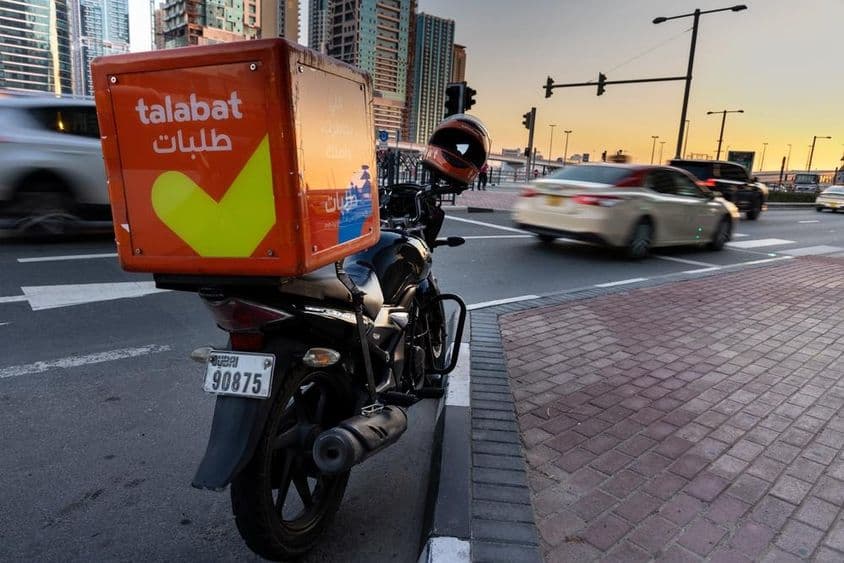 Motocicleta da Talabat estacionada na beira da estrada.