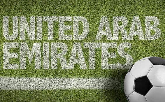 Inscrição de EAU pintada na grama com uma bola de futebol.