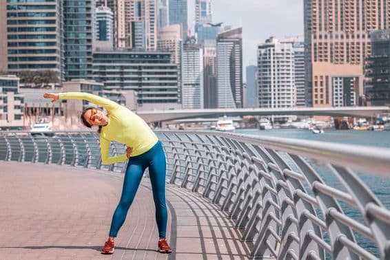 Uma jovem em Dubai se alongando após uma corrida na Marina.