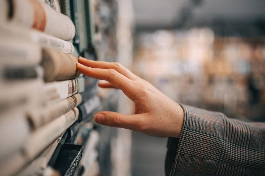 Mão de uma mulher selecionando um livro.