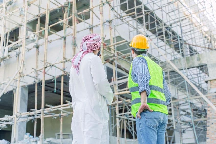 Engenheiro e investidor olhando para um edifício em construção.