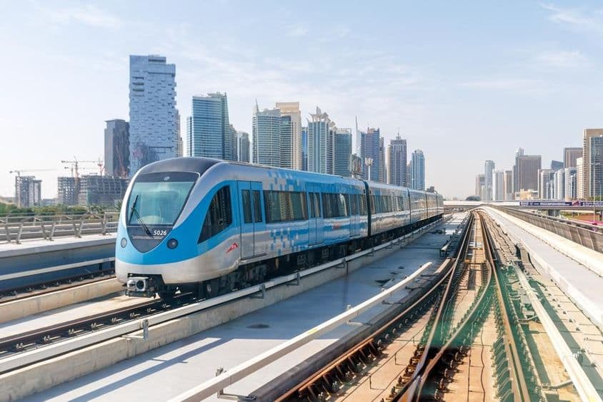 Trem do metrô de Dubai com edifícios ao fundo.