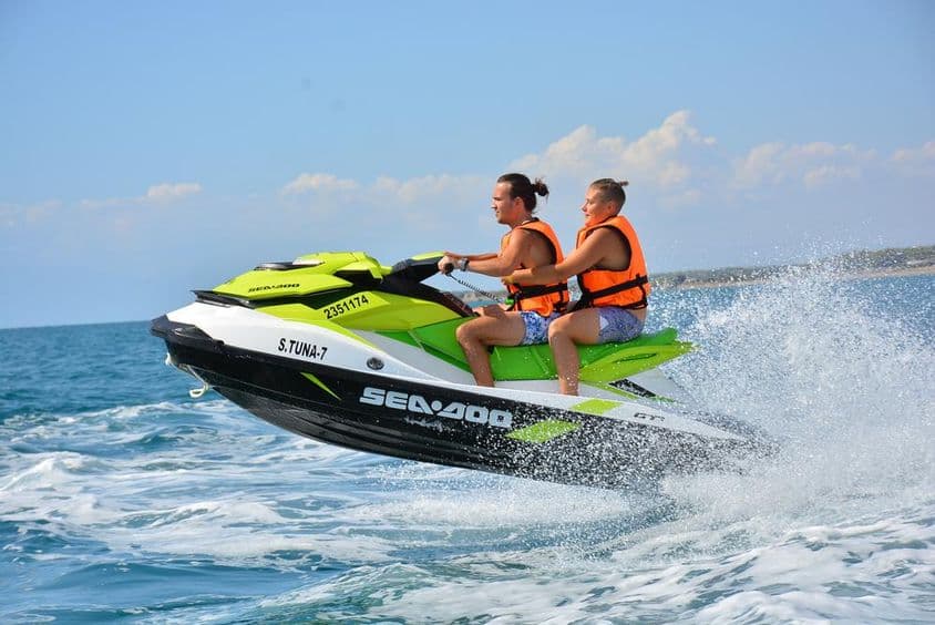 Jovem casal sentado em um jet ski.