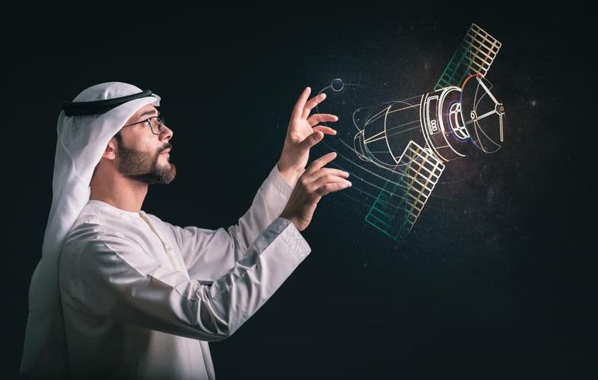Homem muçulmano em frente a satélite projetado.